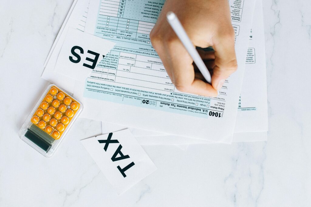 Hand writing notes on financial documents with calculator and business reports.